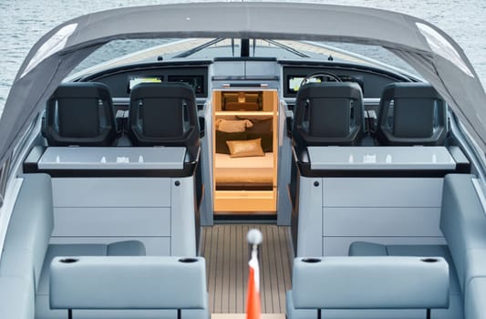 Close-up view of a relaxation area on the open teak deck of an expensive motorboat at sunny day, Monaco yacht show, large boat exhibition, wealth life, table and chairs. High quality photo