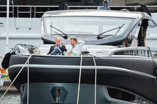 Monaco, Monte Carlo, 29 September 2022 - Invited wealthy clients inspect mega yachts at the largest fair exhibition in the world yacht show MYS, port Hercules, yacht brokers, sunny weather. High quality photo