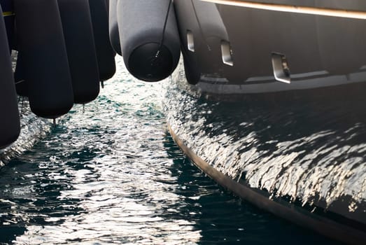 Sun glare on glossy board of mega yacht, anchor, tranquillity in port Hercules, bow of moored huge boat at sunny day, Monaco, Monte-Carlo. High quality photo