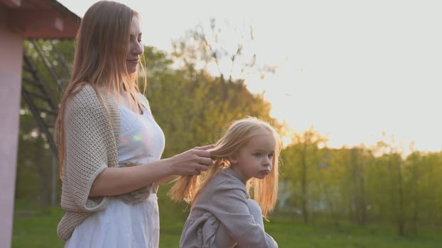 A loving mother touches her daughter's hair at sunset