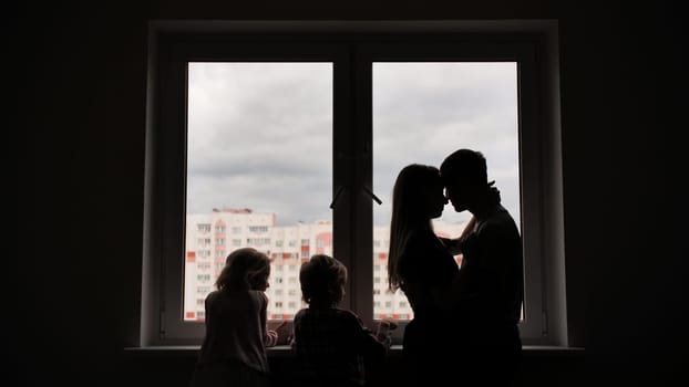 Silhouette of lovers with children on the background of windows from a new apartment