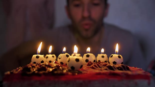 Father football player lights a cake with soccer candles with children