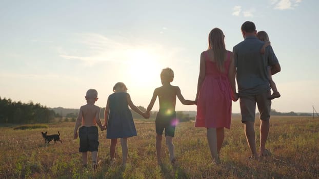 A friendly large family walks across the field at sunset