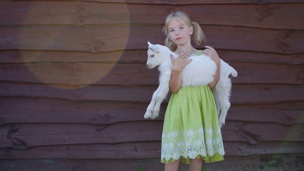 6 year old girl holding a small goat in her arms