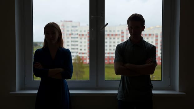 Silhouettes of young spouses against the backdrop of a window in a quarrel