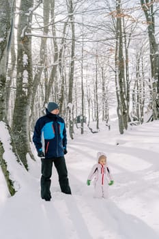 Dad and little girl stand in a snowy forest. High quality photo