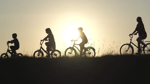 Silhouettes of a large large family on bicycles at sunset