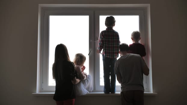 Silhouette of a large family on the background of a window in a new apartment. Quarantine concept