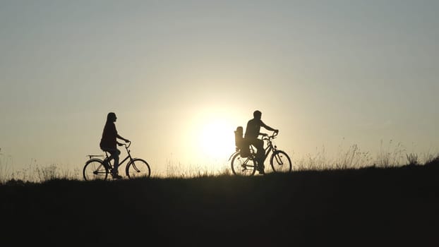 Friendly family with a child on bicycles during sunset