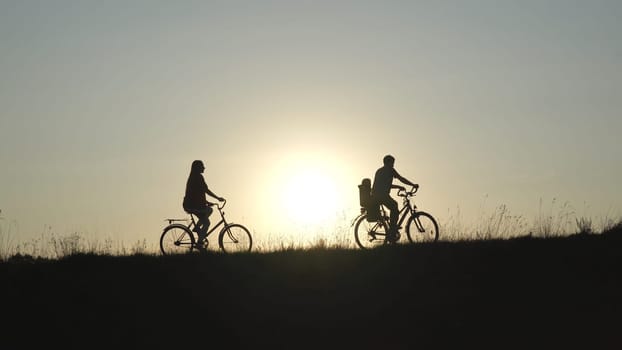 Friendly family with a child on bicycles during sunset