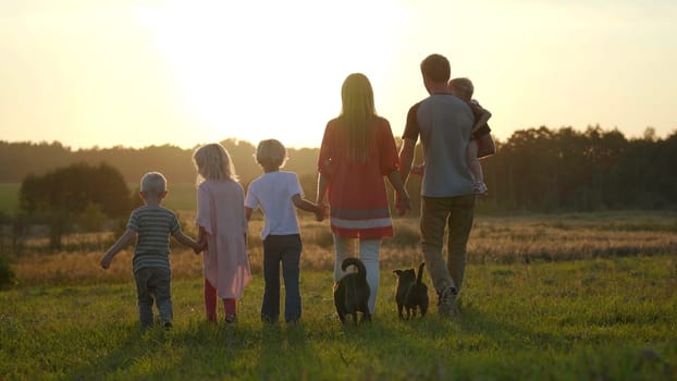 A large friendly family walks across the field at sunset
