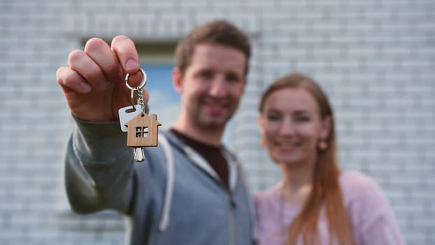 Real estate purchase concept. Young spouses show off keys to the purchased new home