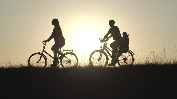Friendly family with a child on bicycles during sunset