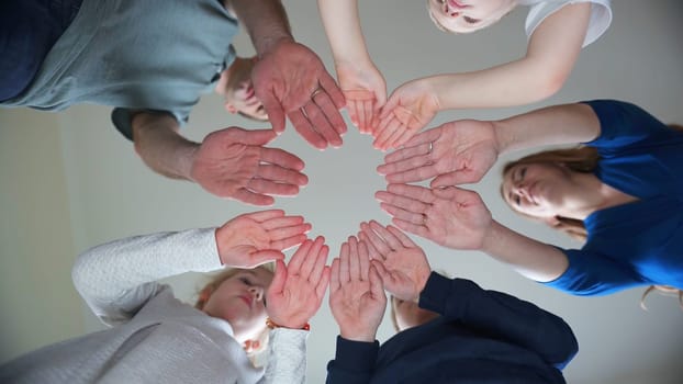 A friendly large family makes a circle shape out of the palms of their hands