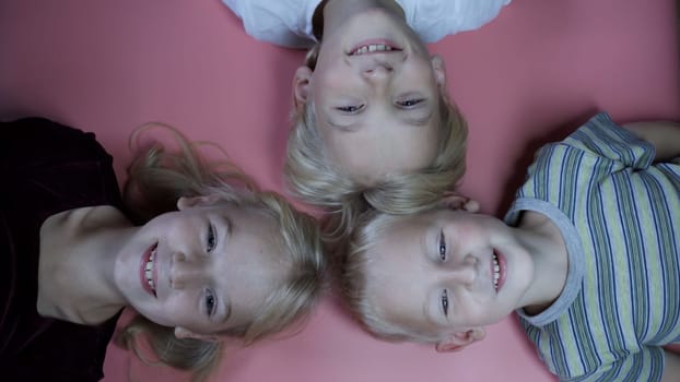 Portrait of little children siblings lying on a pink background