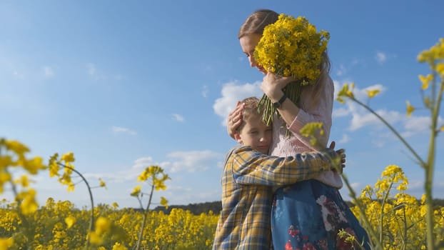 A loving son hugs his mother in a rapeseed field