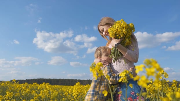 A loving son hugs his mother in a rapeseed field