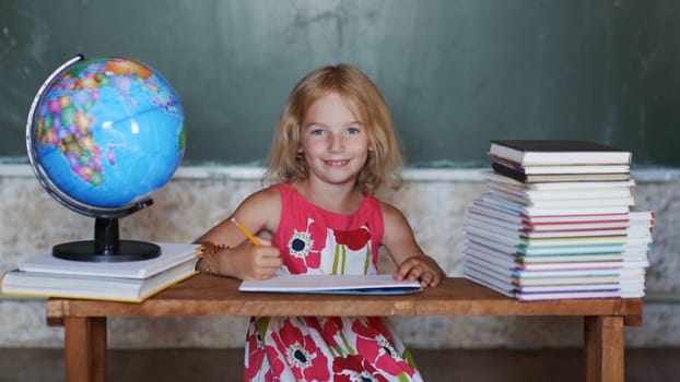 Girl studying at home on the background of the globe and books. Home school concept
