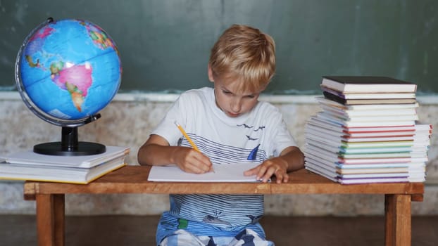 A boy of 8 years old does homework against a background of the globe. Home school concept