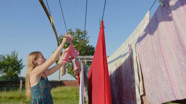 Hardworking mother hangs clothes on the street in the village
