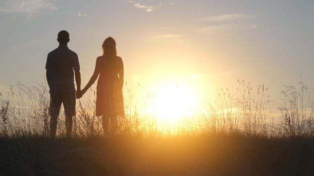 Silhouettes of happy young parents against the background of the evening sun