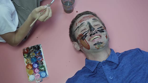 A cheerful father allows his child to paint the face