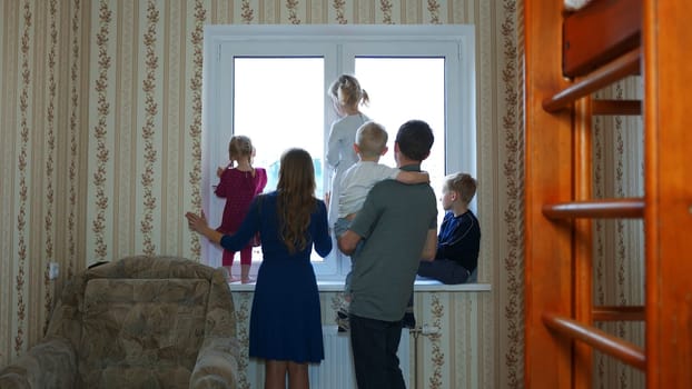 A large and friendly family at the window during quarantine and waved