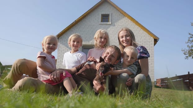 A friendly and large family lies on the grass against the backdrop of their house