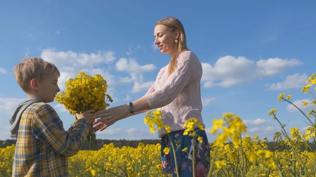 A grateful son gives his mother flowers in a rapeseed field