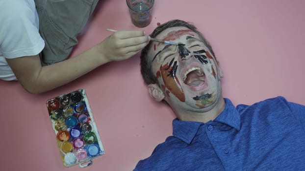 A cheerful father allows his child to paint the face