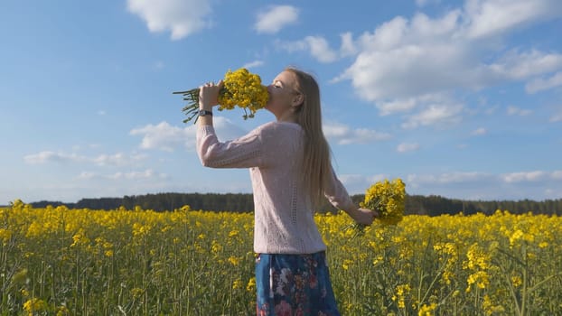 Happy girl with a bouquet of rapeseed flowers in a yellow rapeseed field