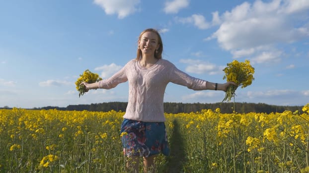 Happy girl with a bouquet of rapeseed flowers in a yellow rapeseed field