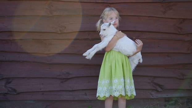 6 year old girl holding a small goat in her arms