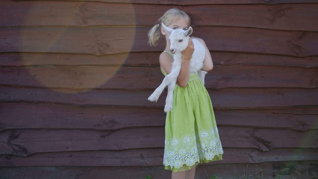 6 year old girl holding a small goat in her arms