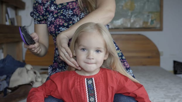 A mother is brushing her two-year-old daughter's hair