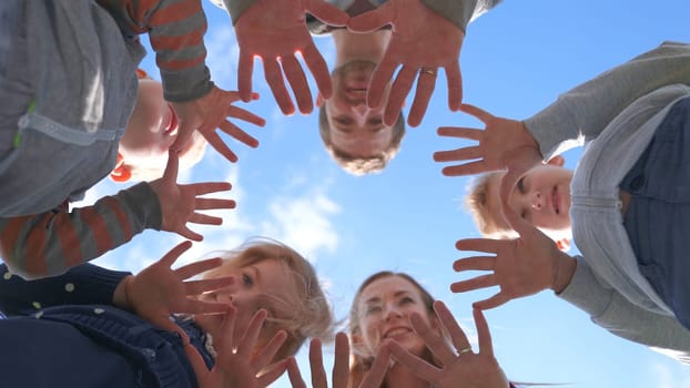 A friendly large family makes a circle shape out of the palms of their hands