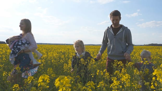A happy family walks on a rapeseed field