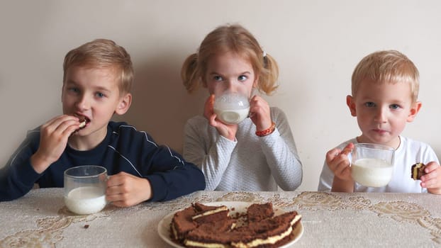 Children at the table eat milk and cookies