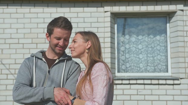 Young happy spouses on the background of their home