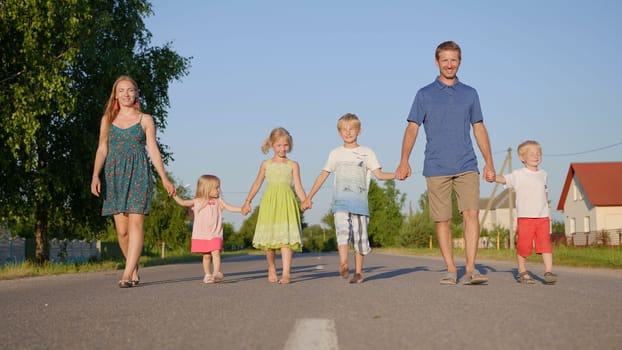 Strong friendly family holding hands goes along the road