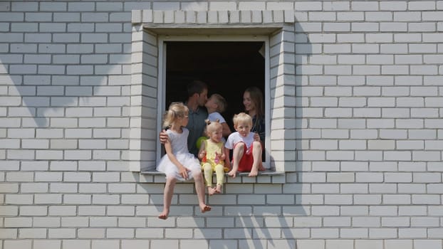 The concept of a large family. A friendly family hugs each other in the window of their house