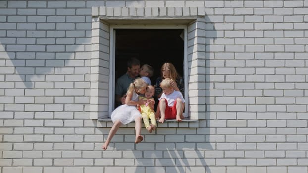 The concept of a large family. A friendly family hugs each other in the window of their house