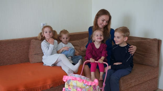 Happy mother of many children with her children on the couch in the house