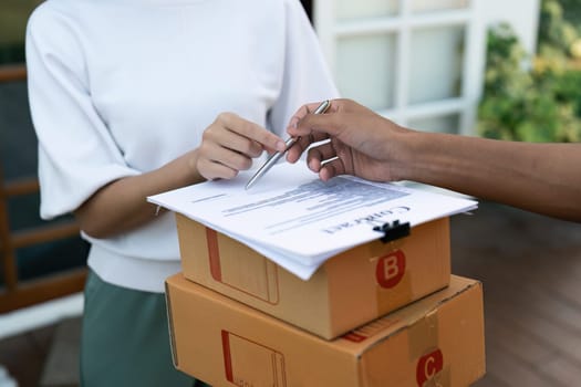 Young woman signature in document to receive package from professional delivery man at home.