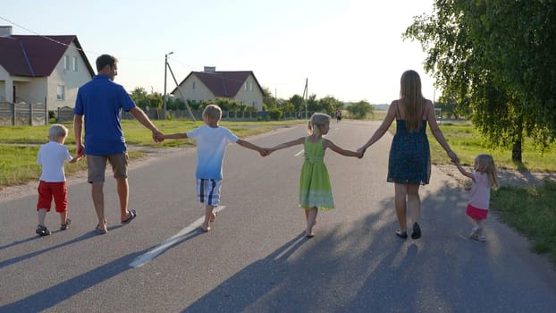 Strong friendly family holding hands goes along the road