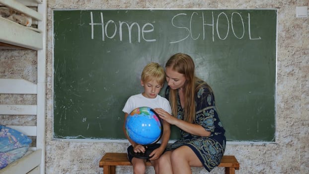 Home school concept. A mother gives her children a geography lesson with a globe in her hands