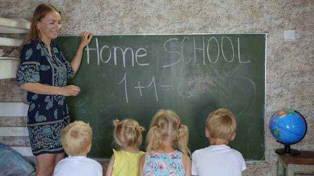 Home school concept. Mother give children a math lesson at the blackboard