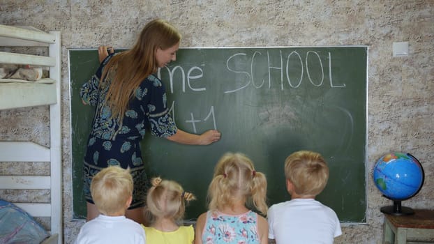 Home school concept. Mother give children a math lesson at the blackboard