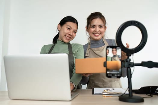 Beautiful asian woman showing clothes for sale in front of camera for live streaming at home.