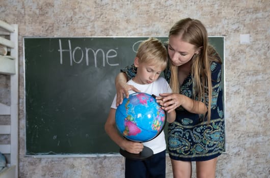 Mother is studying a world map on a globe with her son